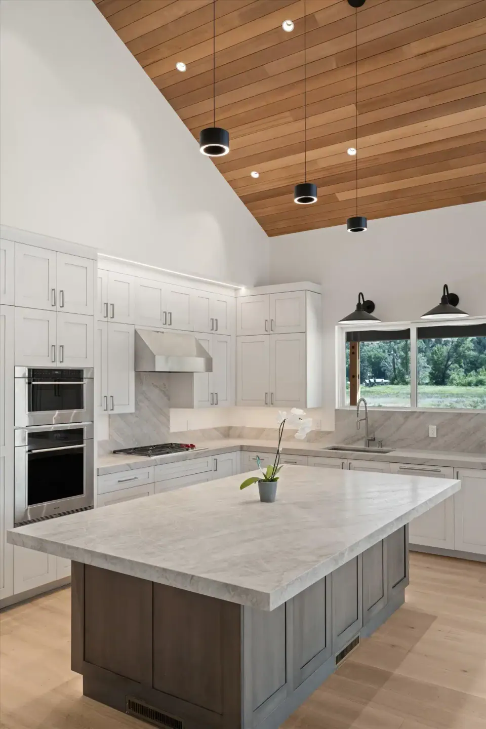 White kitchen with large island under a vaulted wood ceiling